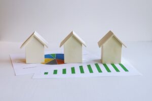 Small house models on financial documents representing cap rate and commercial real estate investment returns